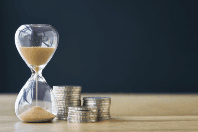 Klepsydra odmierzająca czas z leżącymi obok pieniędzmi